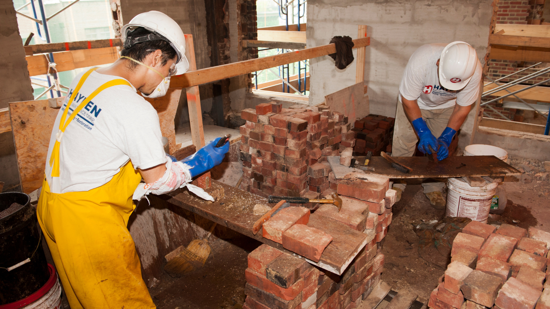 Commercial masonry restoration crew repairing interior brick walls on a construction site